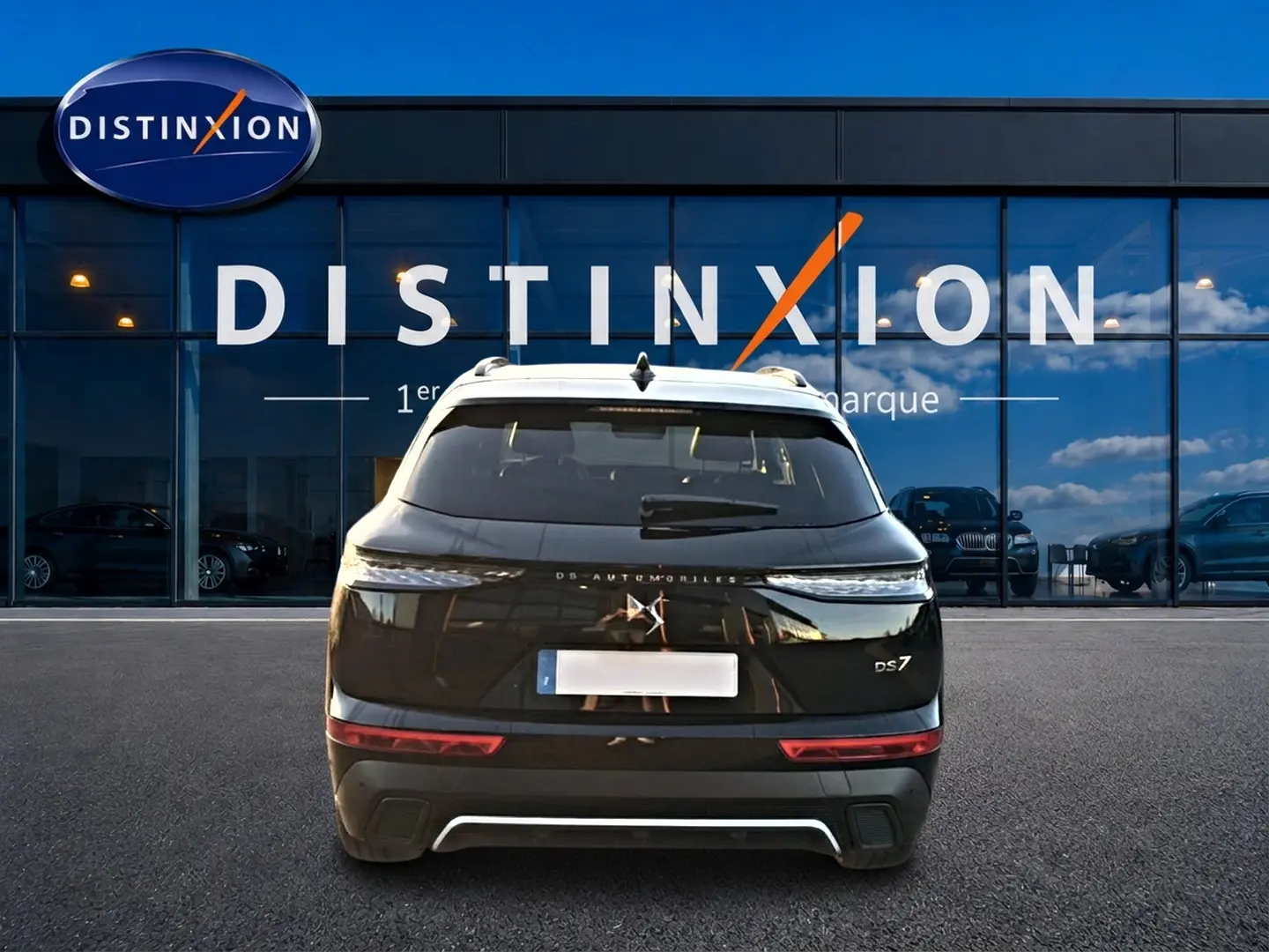 Vue arrière d'un SUV DS7 noir 2026 garé devant une vitrine avec logo Distinxion en arrière-plan.