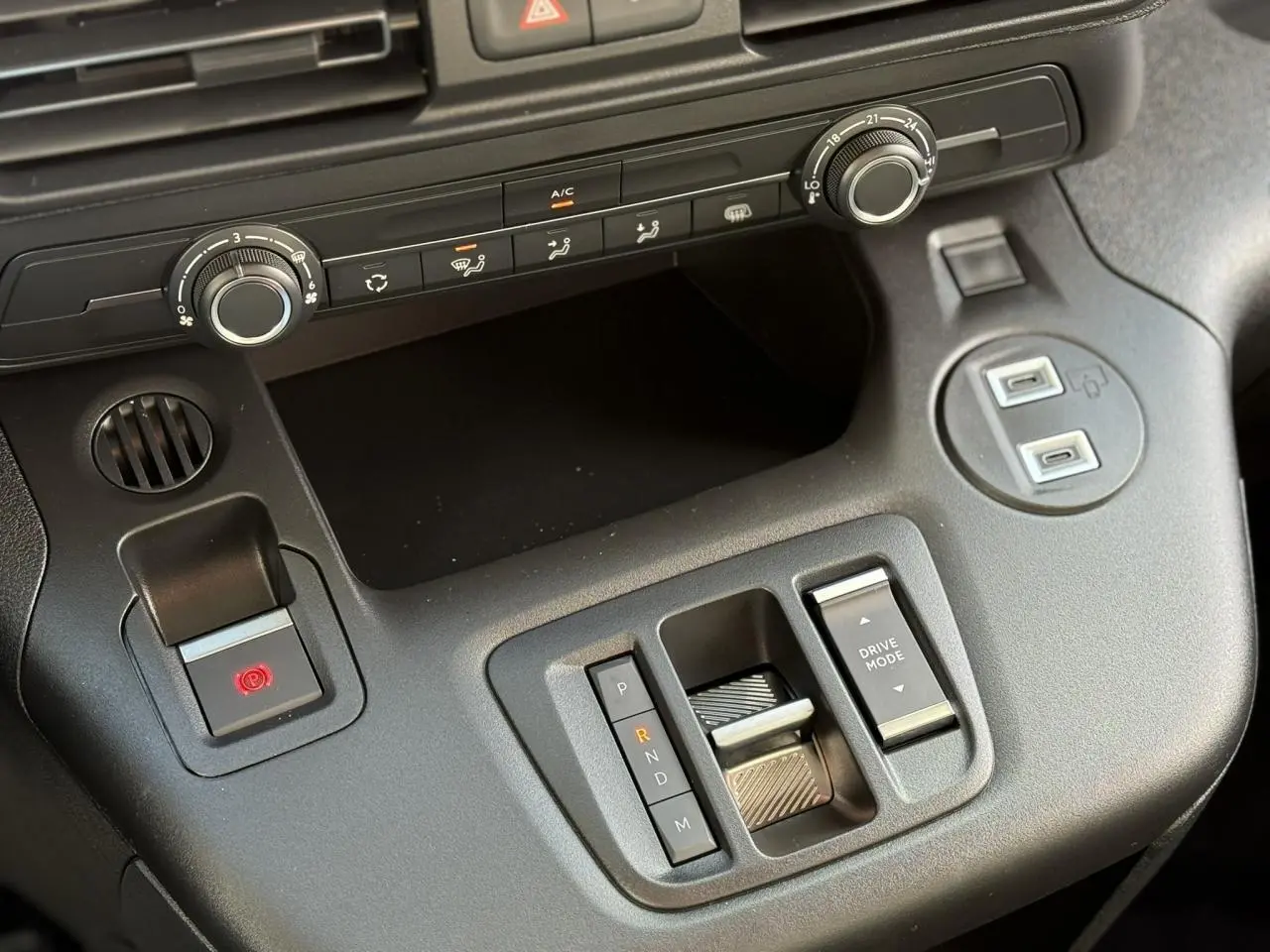 Vue rapprochée de la console centrale noire du Citroën Berlingo 2025 avec boîte auto et commandes climatisation.