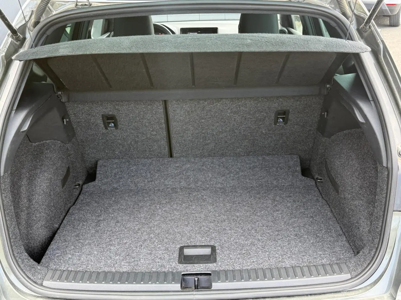 Coffre ouvert vu de l'arrière d'un SEAT Arona Gris Cliff, montrant un plancher plat et une moquette grise uniforme.