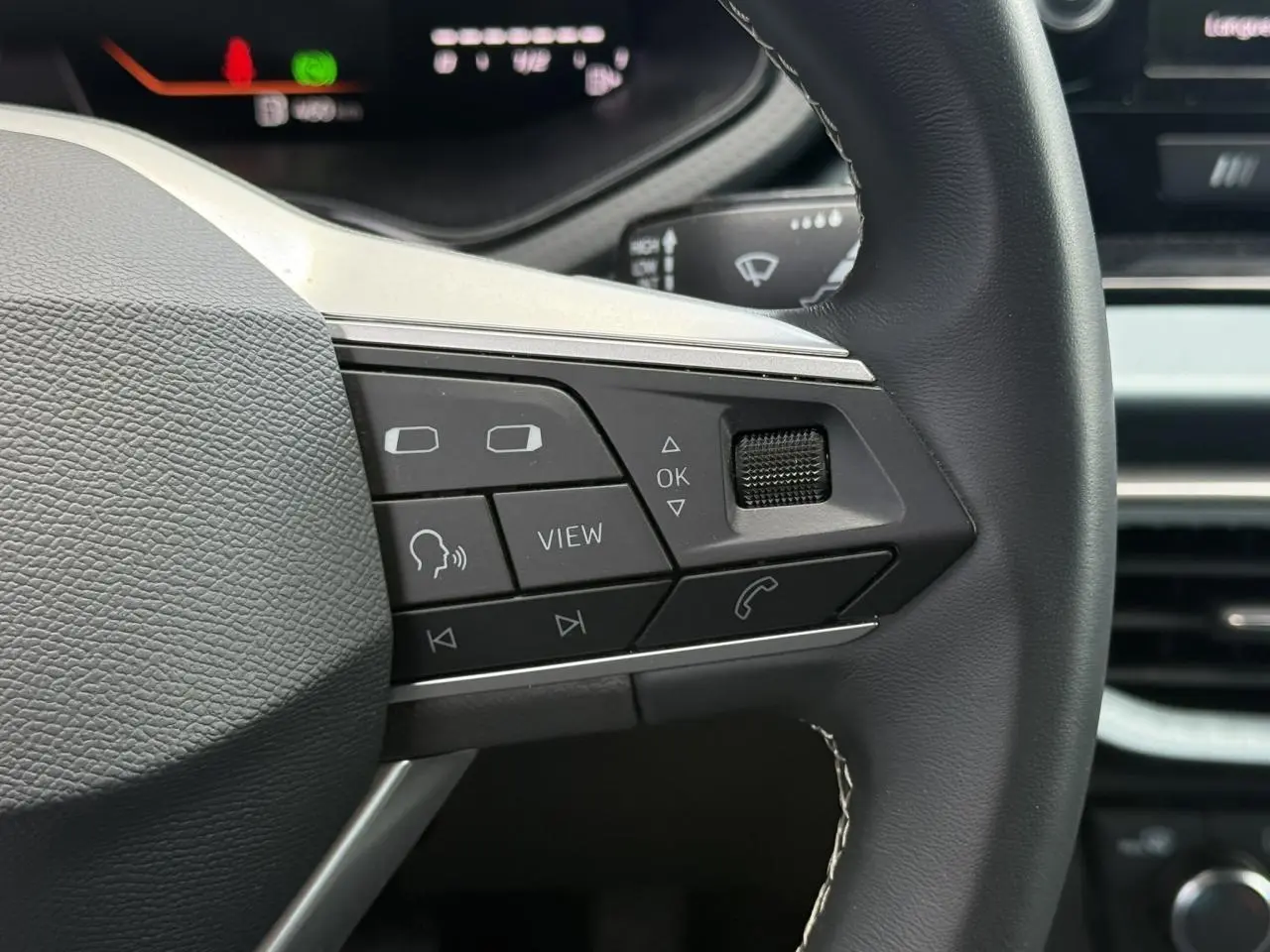Gros plan sur les commandes à droite du volant noir du SEAT Arona 2025, avec affichage digital en arrière-plan.