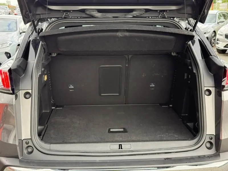 Coffre ouvert vu de l'arrière du Peugeot 3008 Gris Platinium 2024, montrant un espace de chargement vide et propre.