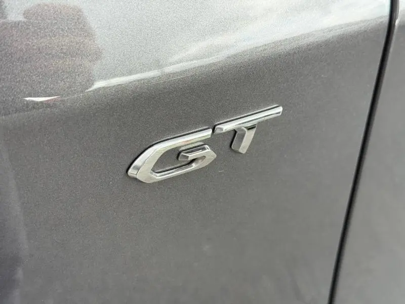 Gros plan sur l’inscription GT chromée sur la porte côté droit d’un Peugeot 3008 Gris Platinium 2024.