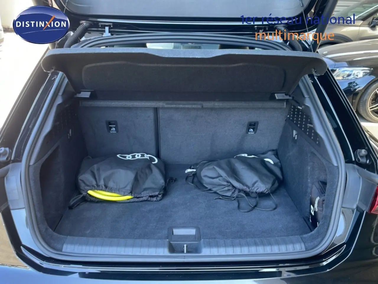 Coffre ouvert vu de l'arrière d'une Audi A3 Sportback noir mito metal avec deux sacs noirs à l'intérieur.