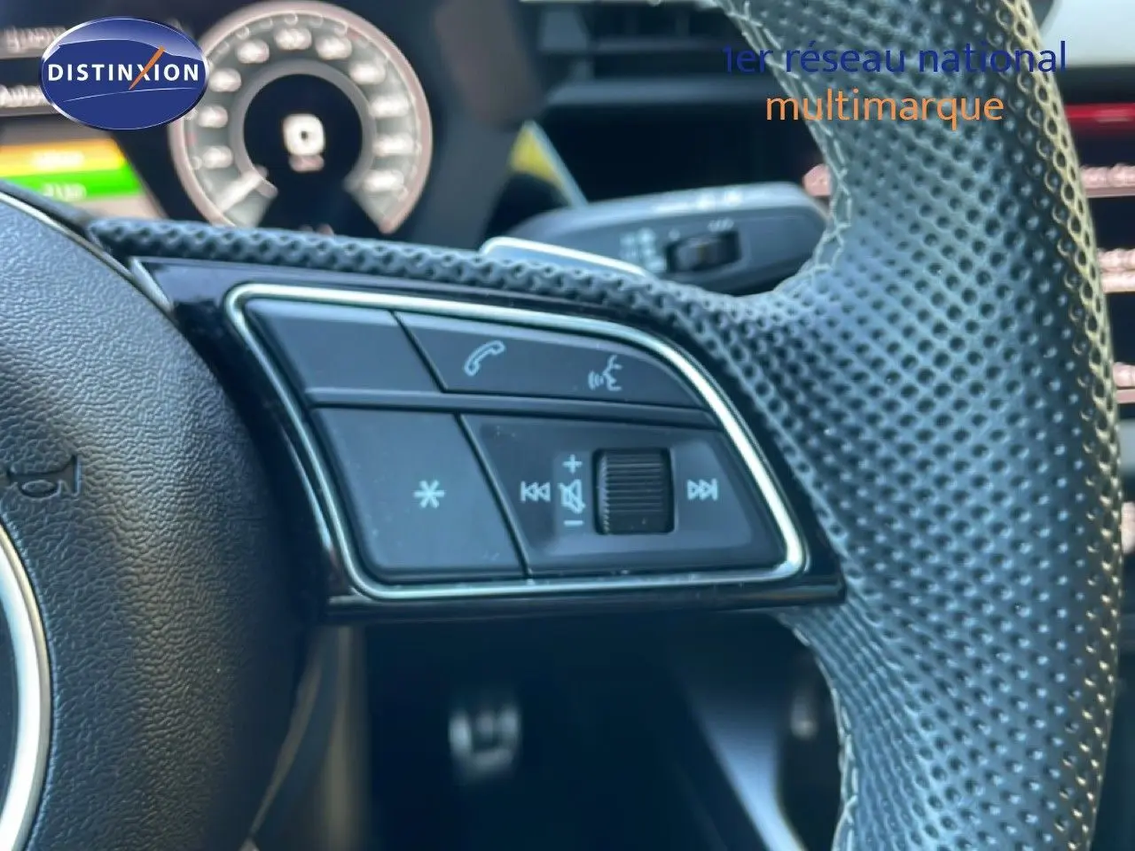 Gros plan sur les commandes gauche du volant perforé noir de l'Audi A3 Sportback 40 TFSIe 2025.