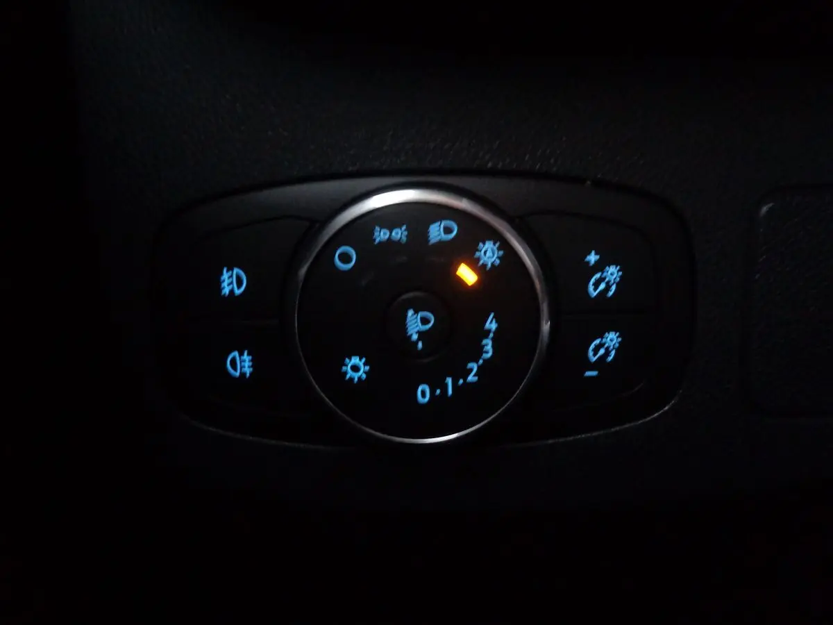 Gros plan sur la commande d'éclairage du Ford Puma blanc 2022, avec voyants bleus et orange allumés.