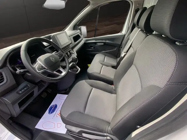 Intérieur du Renault Trafic Fourgon blanc 2025, vue côté conducteur sur sièges tissu noir et tableau de bord moderne.