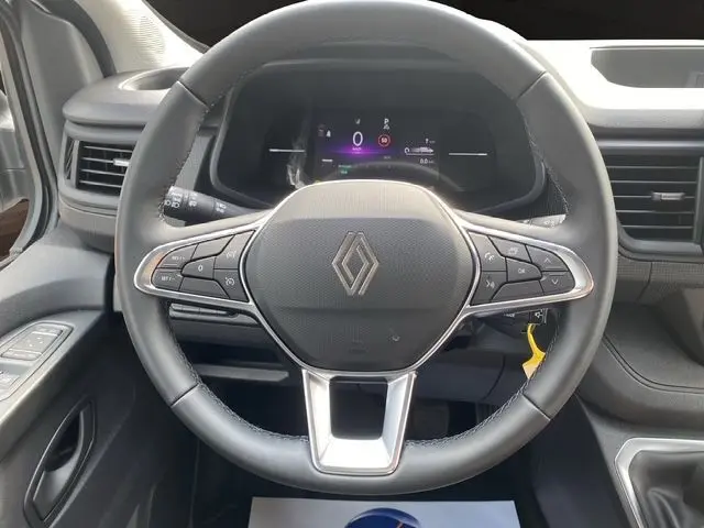 Vue rapprochée du volant cuir noir du Renault Trafic Fourgon 2025 avec commandes multifonctions et tableau de bord digital.