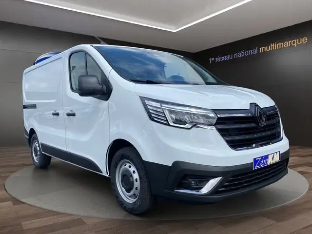 Renault Trafic Fourgon blanc en 3/4 avant droit, avec calandre noire et feux LED, présenté en showroom.