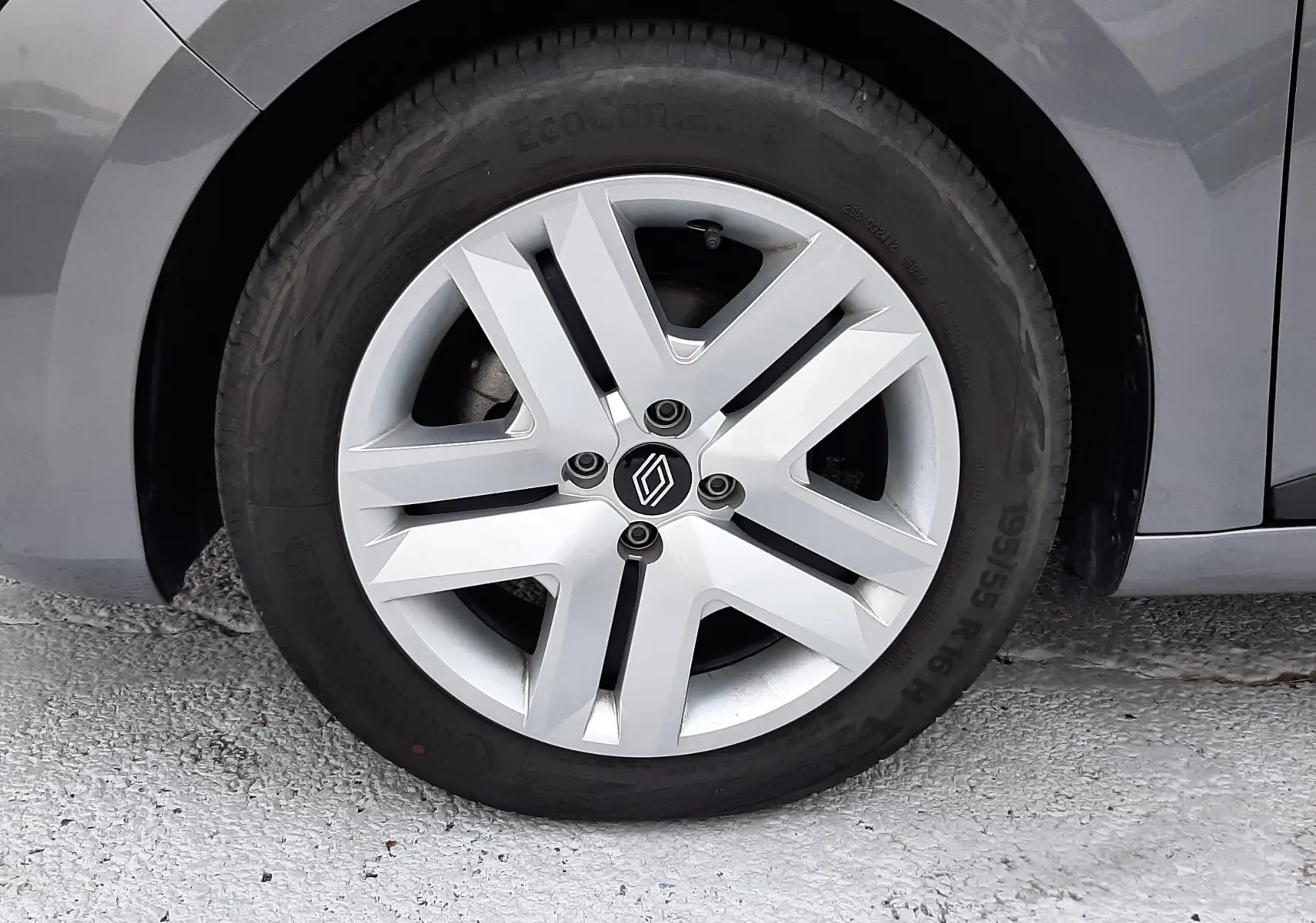 Gros plan sur la roue avant gauche de la Renault Clio V gris schiste, mettant en valeur la jante aluminium au design moderne.