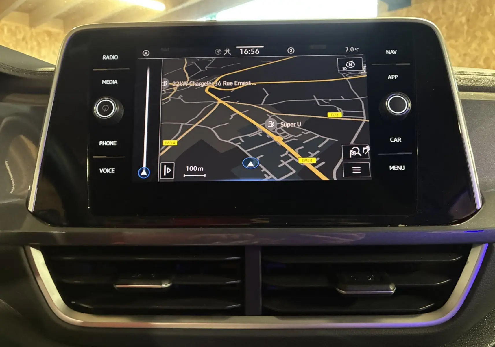 Écran tactile central du Volkswagen T-Roc gris 2023 montrant la navigation GPS avec commandes autour et aérateurs en dessous.