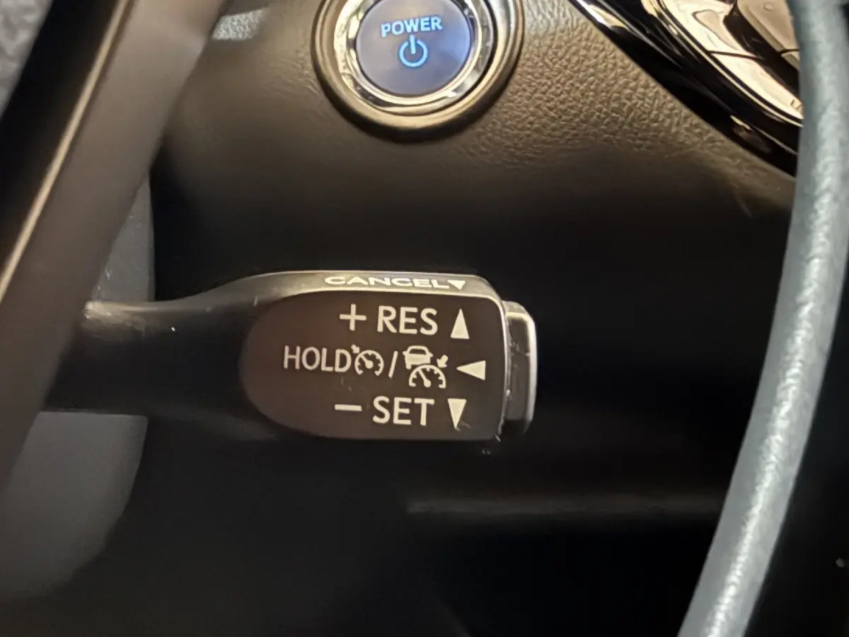 Gros plan sur la commande du régulateur de vitesse au volant cuir du Toyota C-HR gris foncé 2022.