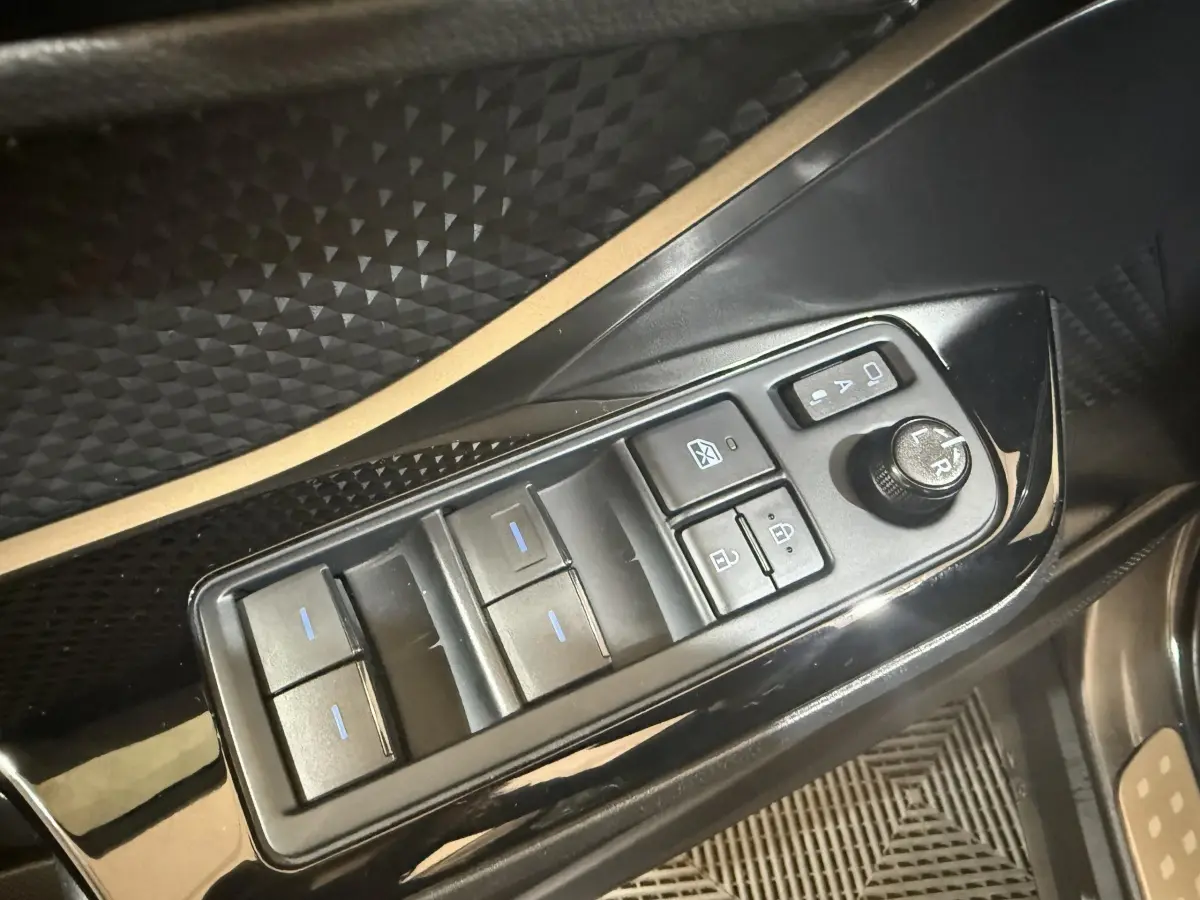 Gros plan sur les commandes de lève-vitres et rétroviseurs noirs dans l'habitacle du Toyota C-HR gris foncé.