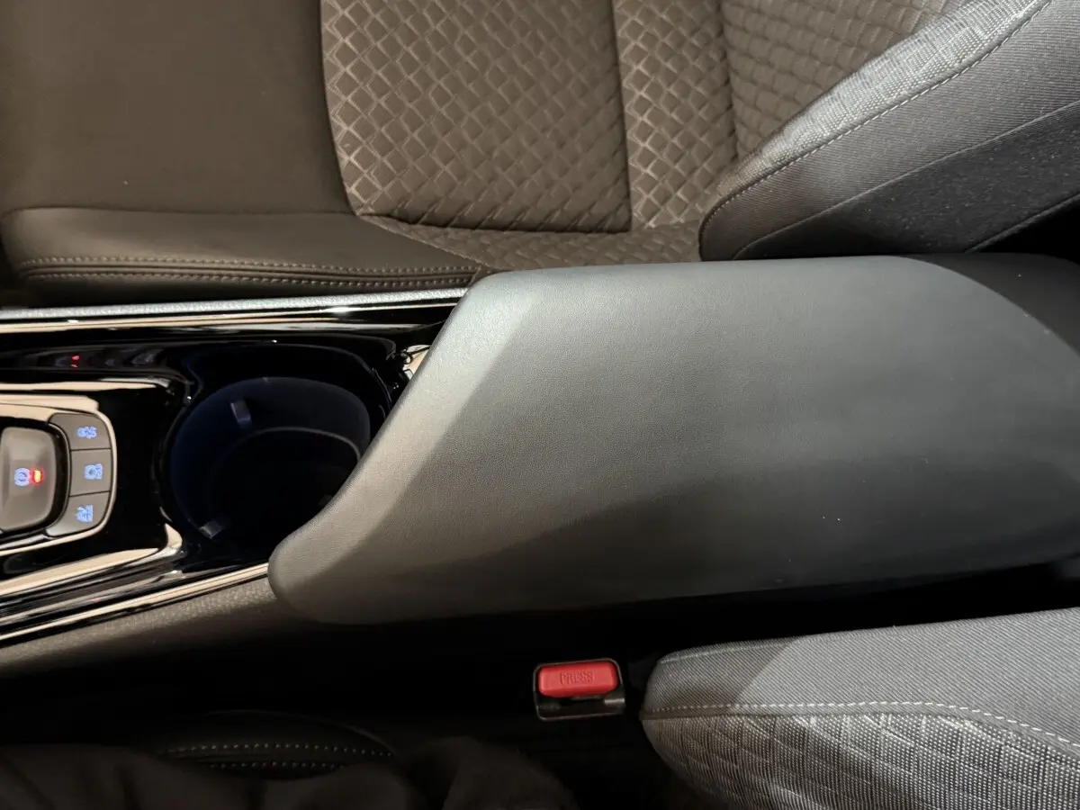Détail de l'accoudoir central noir et du siège gris à motifs du Toyota C-HR 1.8 Hybride 122 Edition 2022.