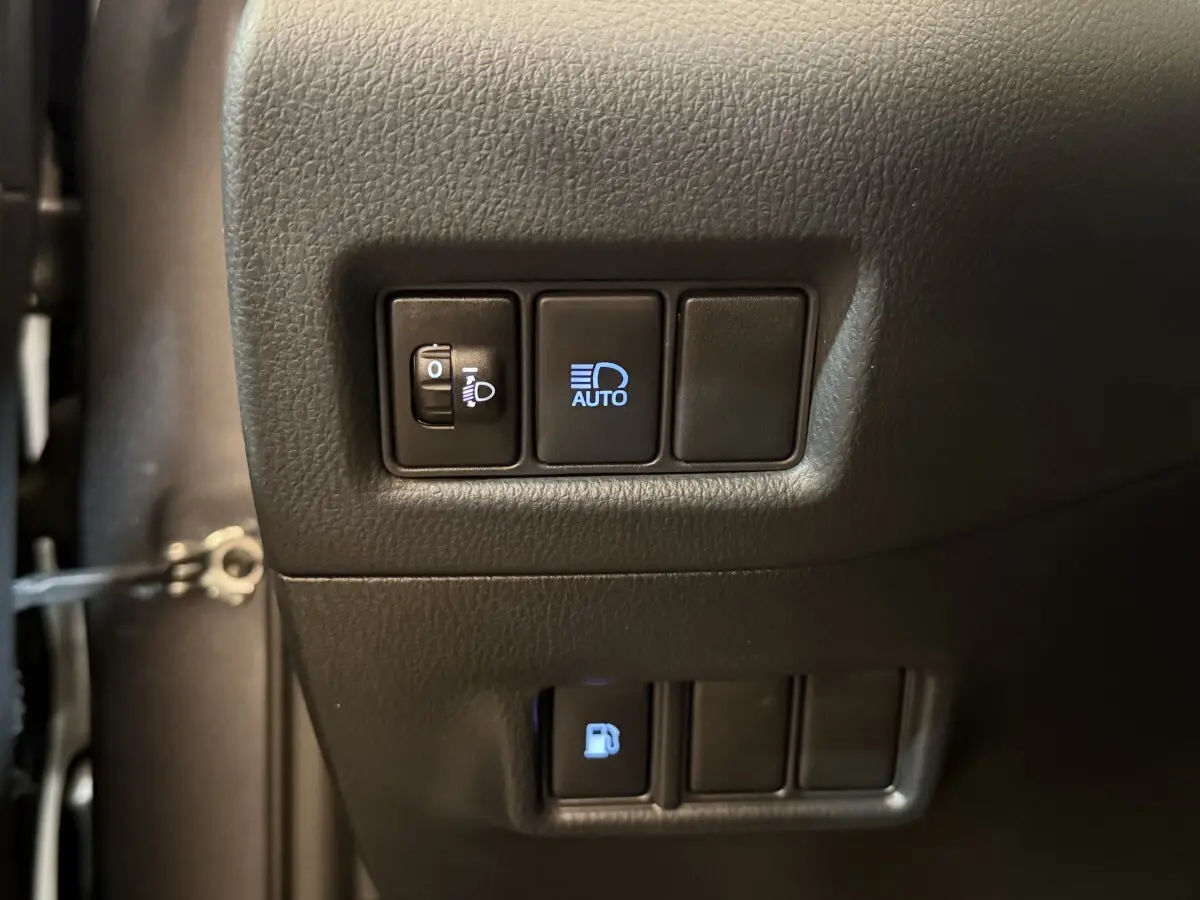 Gros plan sur les commandes d'éclairage et ouverture du réservoir du Toyota C-HR gris foncé, côté gauche intérieur.