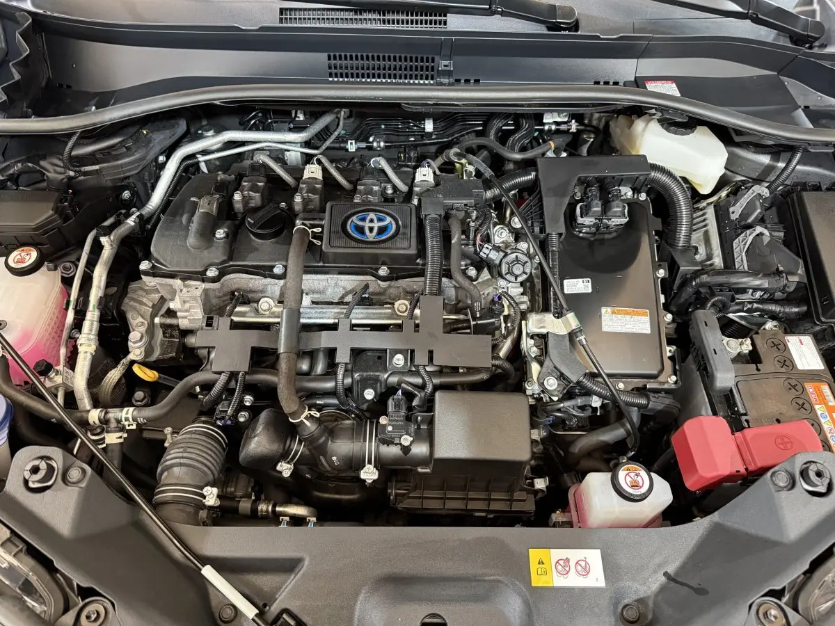 Vue plongeante sur le moteur hybride Toyota C-HR 1.8 gris foncé, avec logo Toyota visible au centre du moteur.