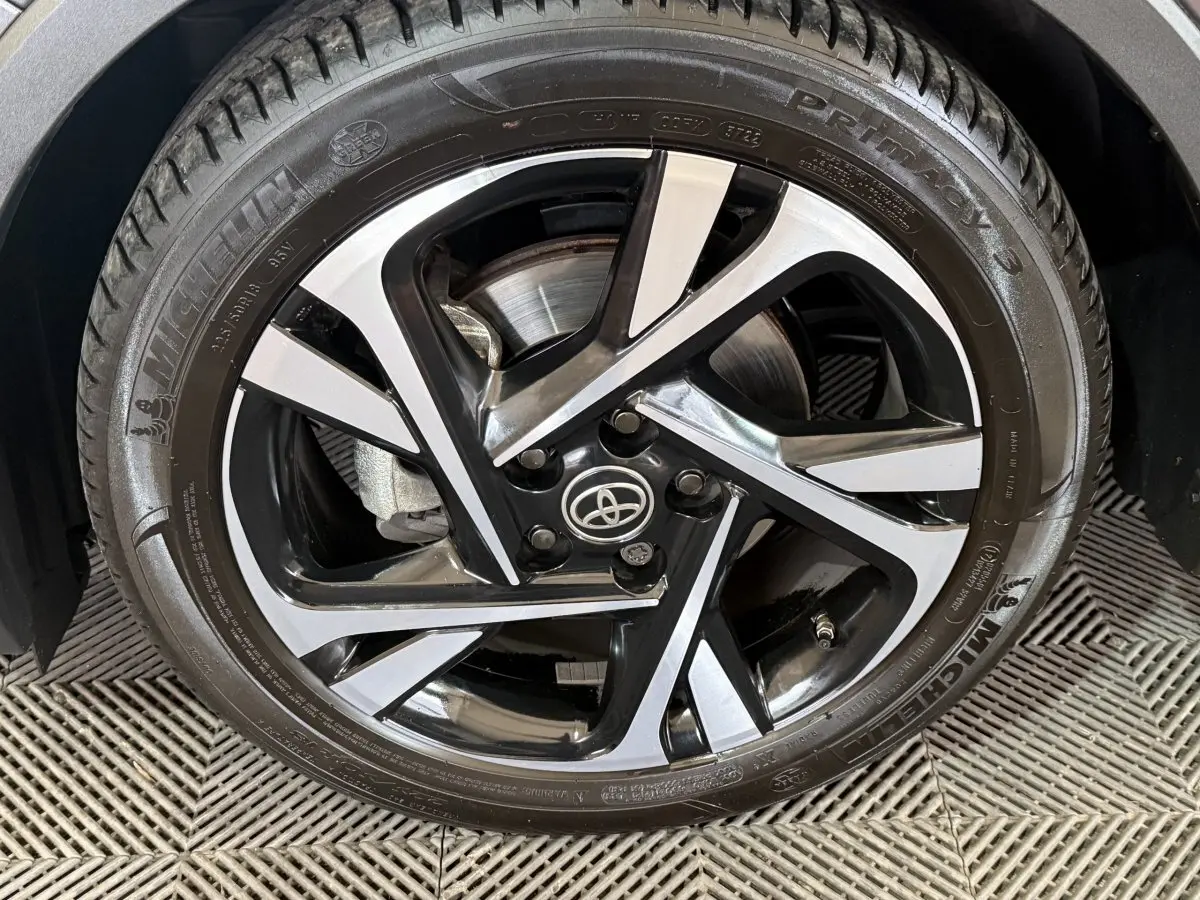 Gros plan sur la jante alliage bicolore noire et argentée d’un Toyota C-HR gris foncé, roue avant droite.