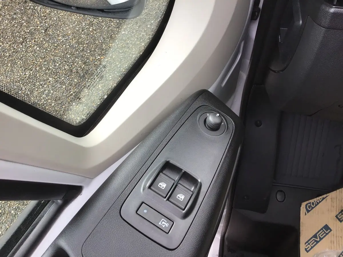 Gros plan sur les commandes de lève-vitres et réglage des rétroviseurs côté conducteur du Fiat Ducato blanc 2023.