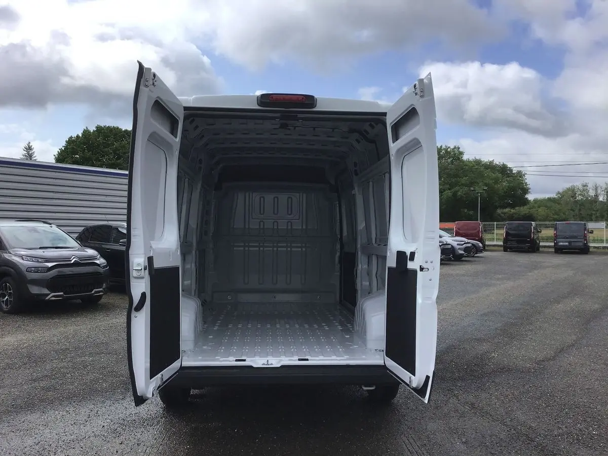 Vue arrière d'un FIAT Ducato Fourgon blanc 2023 avec portes ouvertes montrant l'espace de chargement vide.