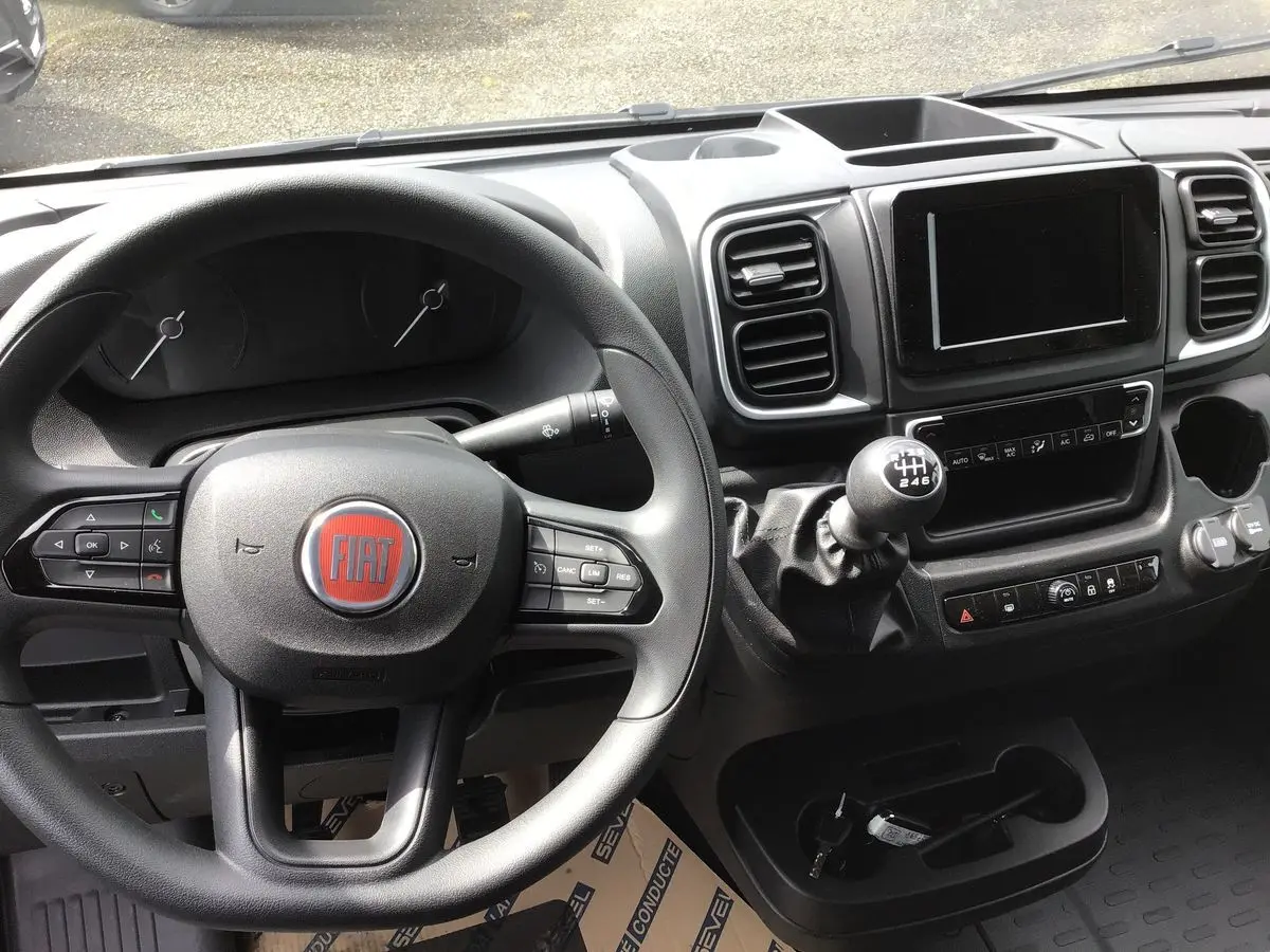 Vue intérieure du tableau de bord et volant du Fiat Ducato Fourgon 2023 avec boîte manuelle et écran tactile central.