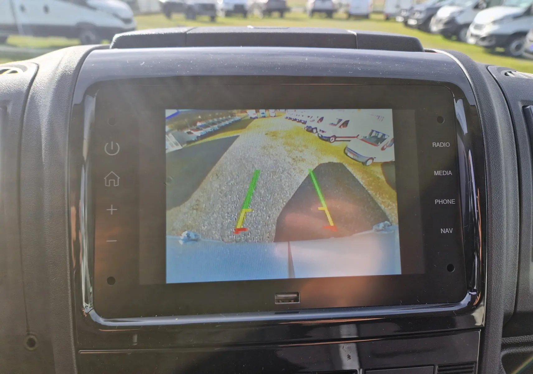 Écran de caméra de recul affichant l'arrière d'un Citroën Jumper blanc avec des lignes de guidage colorées.