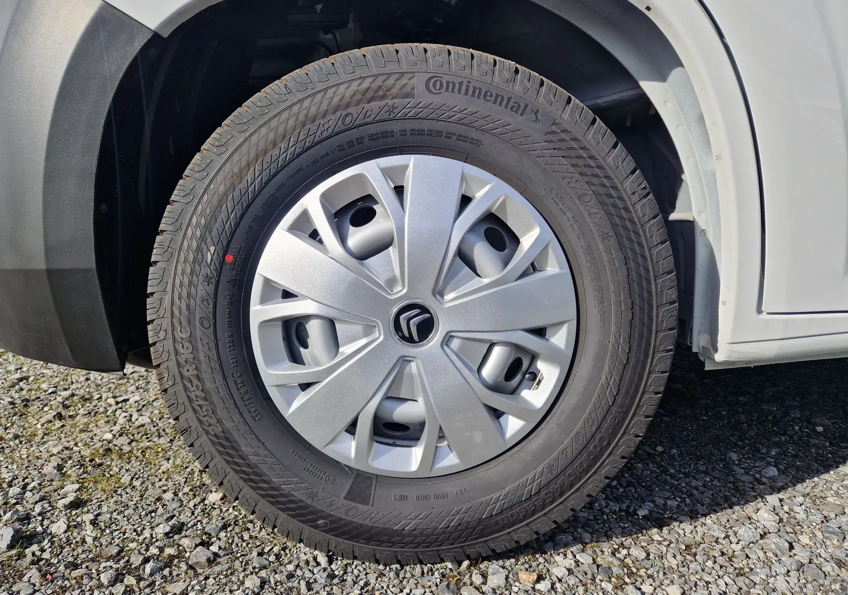 Gros plan sur la roue avant gauche d'un Citroën Jumper blanc, avec jante en plastique et pneu Continental.