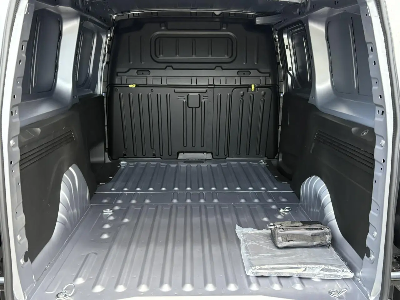 Vue intérieure de la zone de chargement grise Artense du Citroën Berlingo Van XL 2025, avec rangement et trappe visible.