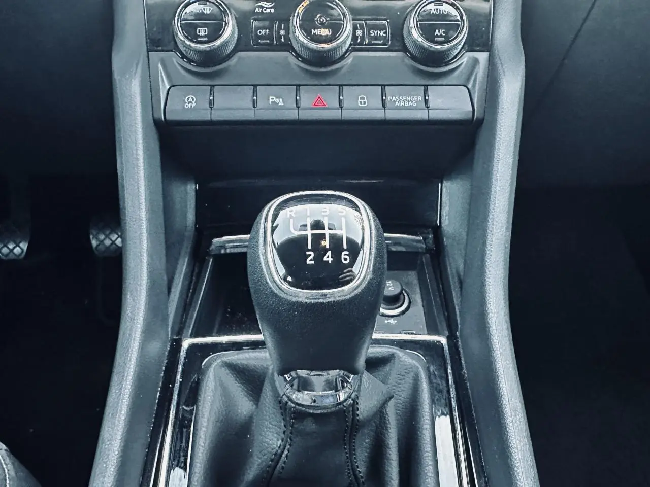 Gros plan sur le levier de vitesse manuel noir du Skoda Karoq 2024, entouré de la console centrale et commandes de climatisation.