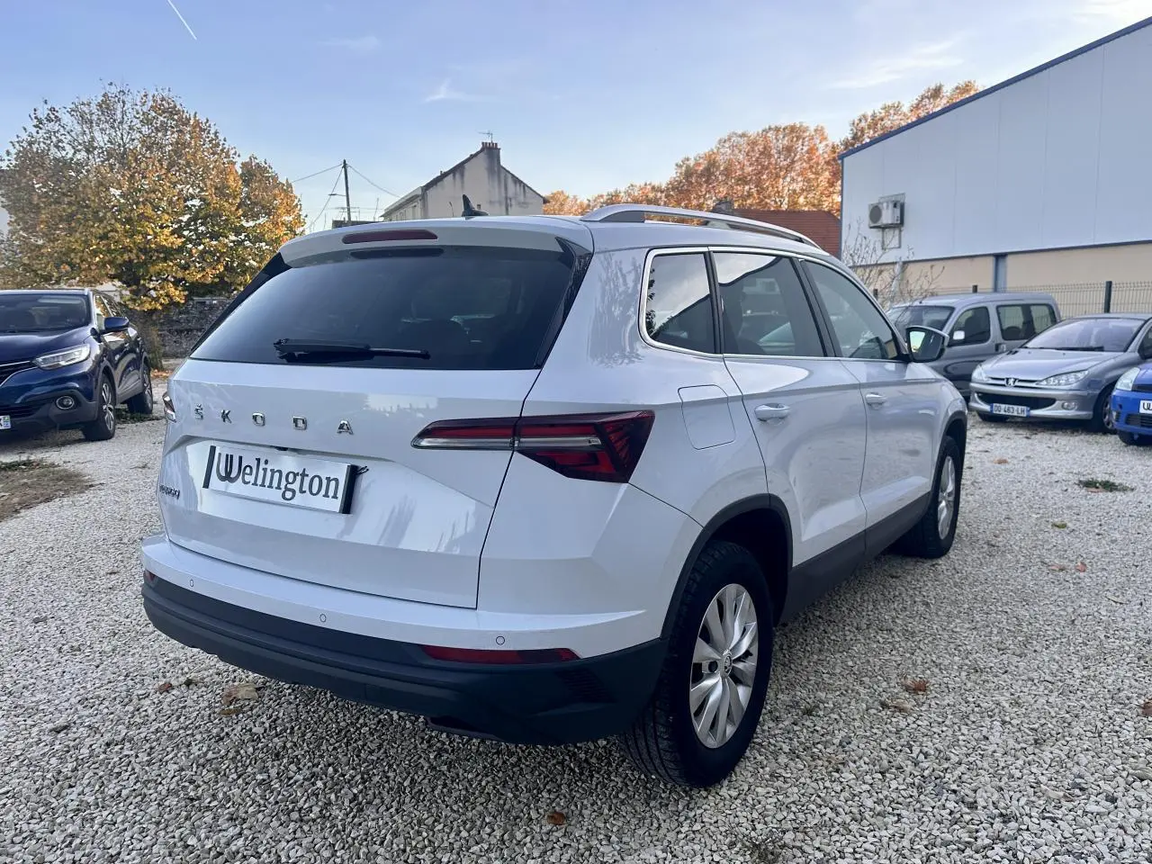 Vue 3/4 arrière droite d’un Skoda Karoq blanc 2024 avec vitres teintées et feux arrière LED distinctifs.