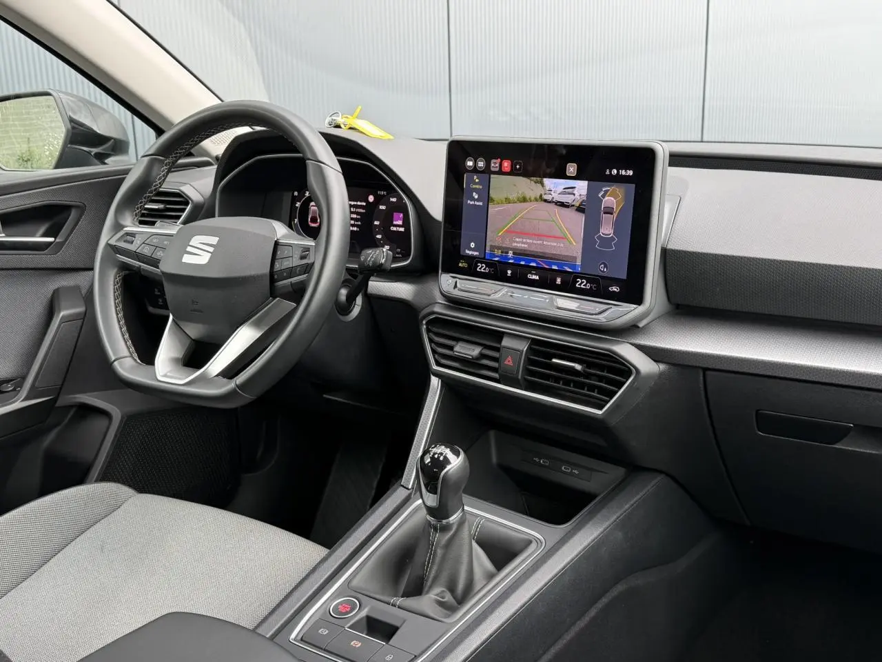 Intérieur avant droit du SEAT Leon noir Minuit, volant cuir multifonction et écran tactile avec caméra de recul affichée.