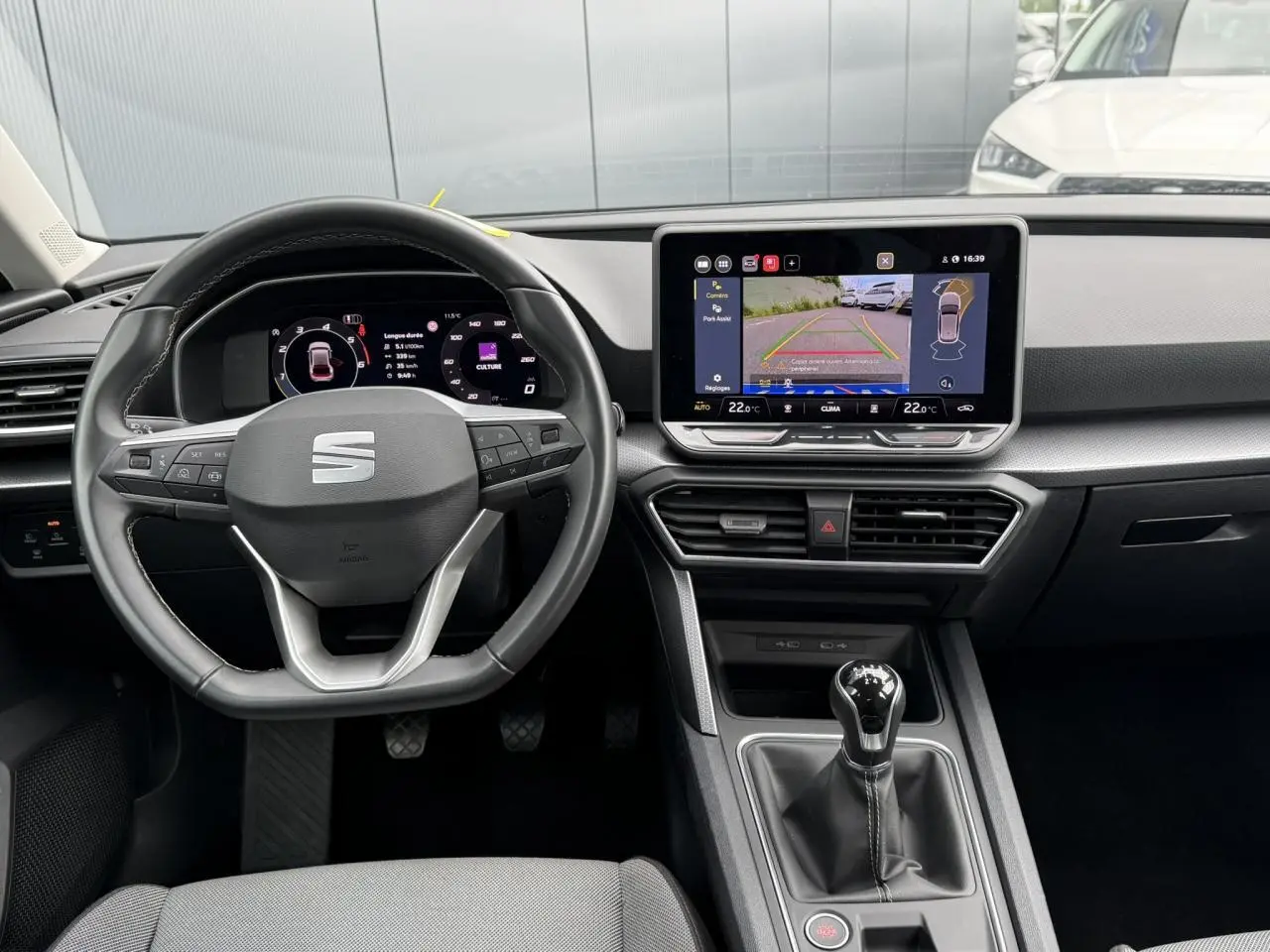 Vue intérieure du tableau de bord et volant cuir multifonction d'une SEAT LEON 2.0 TDI 115 Style avec écran tactile et caméra de recul.