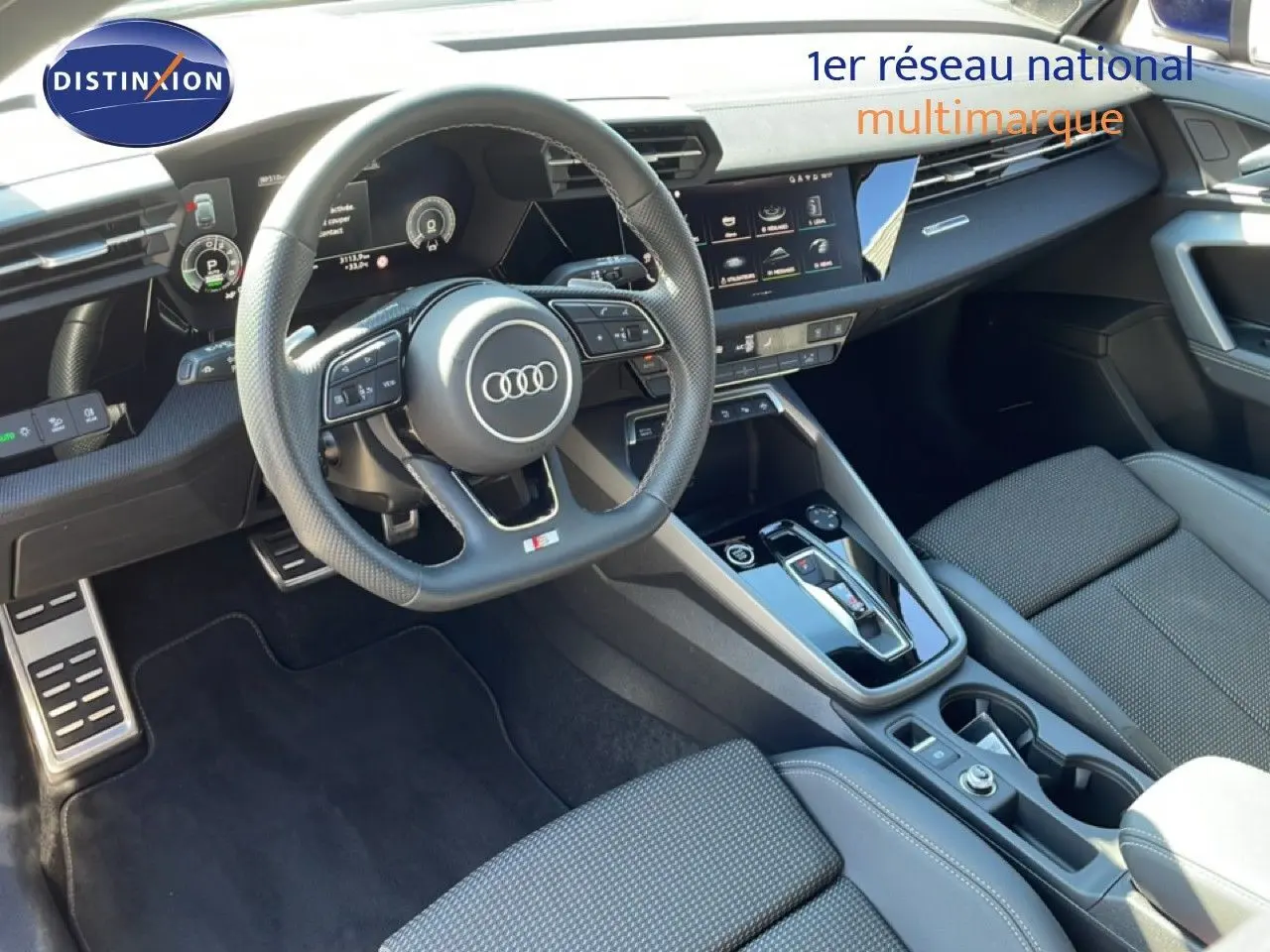 Vue intérieure de l'Audi A3 Sportback 2025, tableau de bord et volant cuir noir avec écran tactile central.