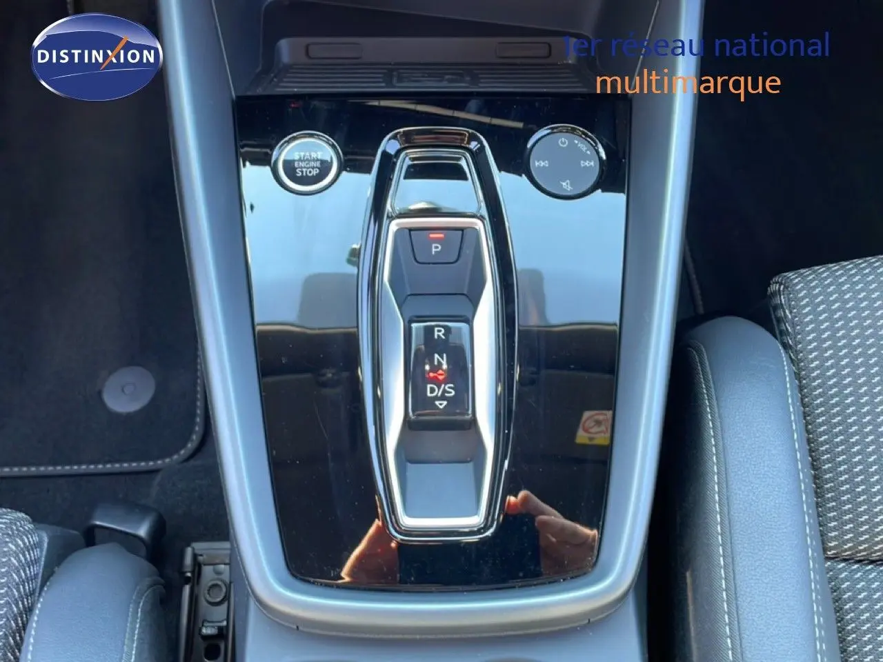 Vue rapprochée de la console centrale noire brillante avec sélecteur de boîte automatique et bouton start/stop dans un Audi A3 Sportback bleu Navarre.