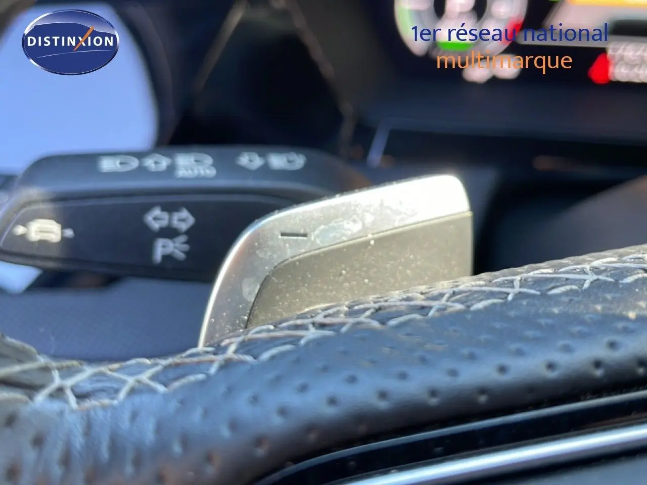Gros plan sur la palette de changement de vitesse derrière le volant en cuir perforé de l'Audi A3 Sportback 2025.