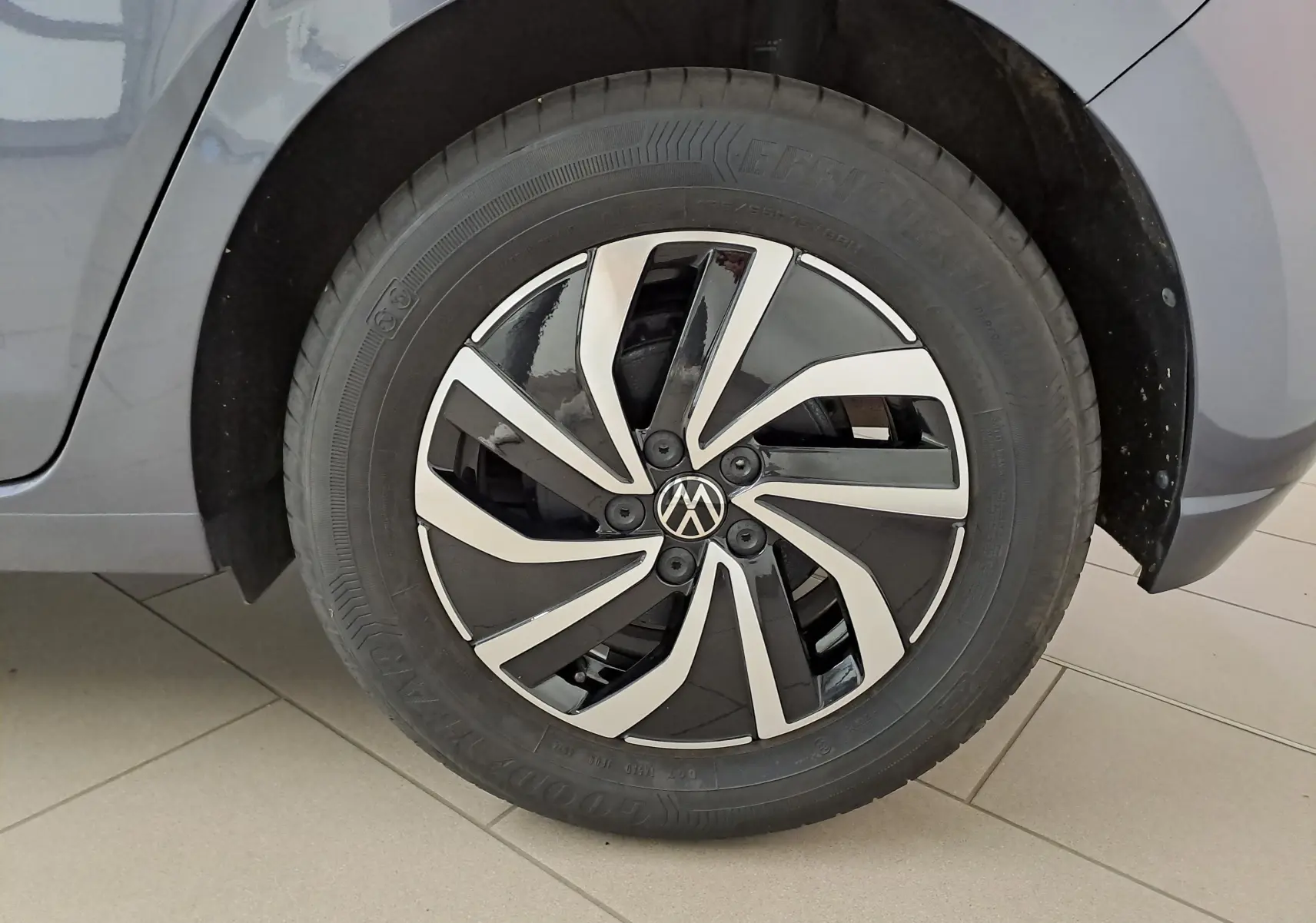 Gros plan sur la roue avant droite d'une Volkswagen Polo gris cendre avec jante alliage bicolore au design moderne.
