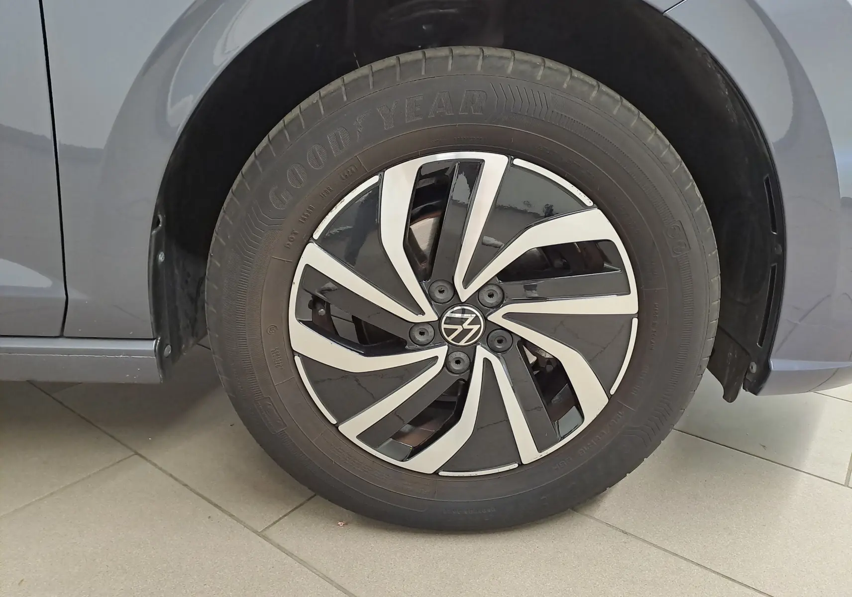 Gros plan sur la roue avant gauche d'une Volkswagen Polo gris cendre avec jante alliage bicolore moderne.