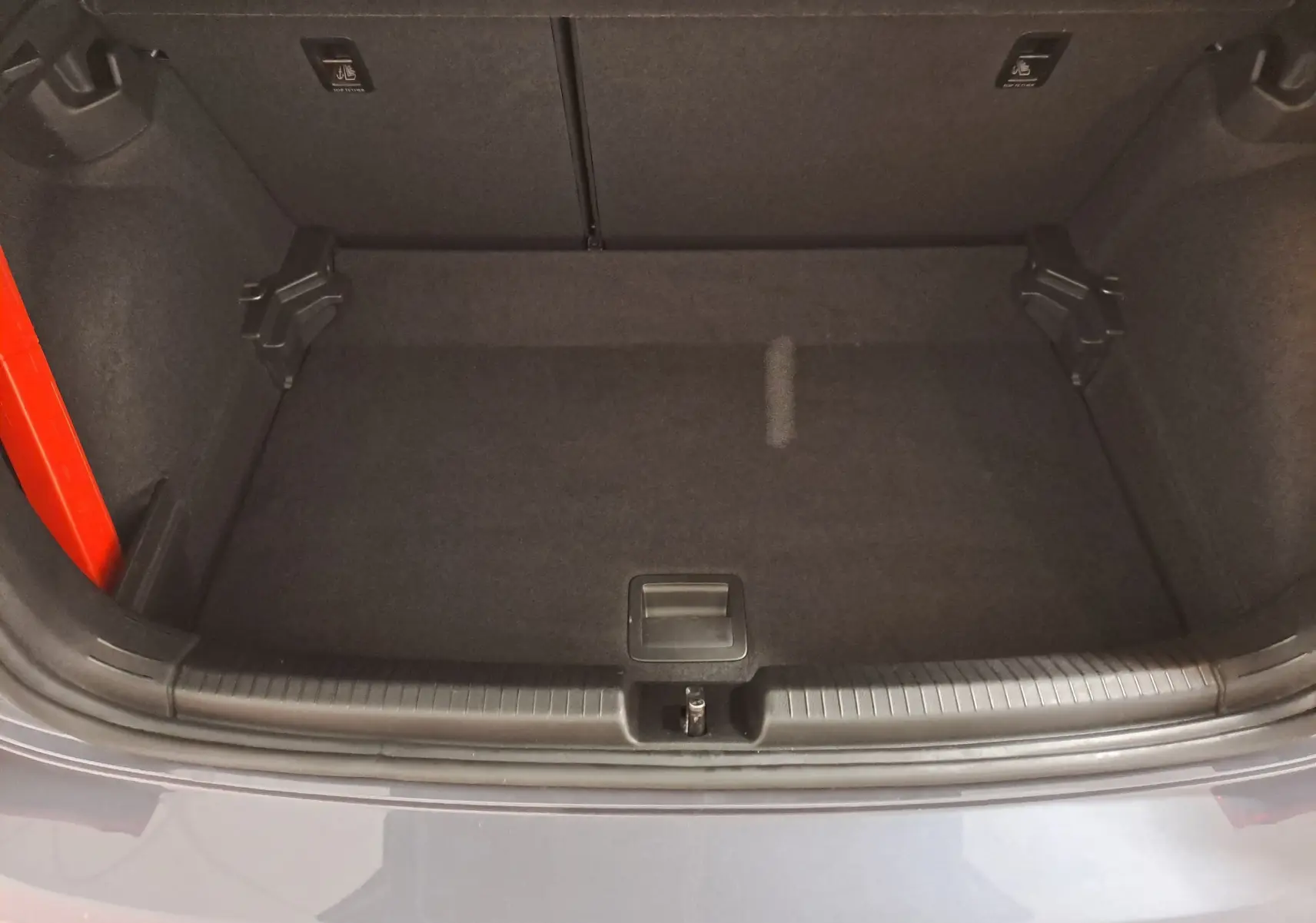 Coffre ouvert vu de dessus d'une Volkswagen Polo gris cendre, montrant un espace de rangement propre et vide.