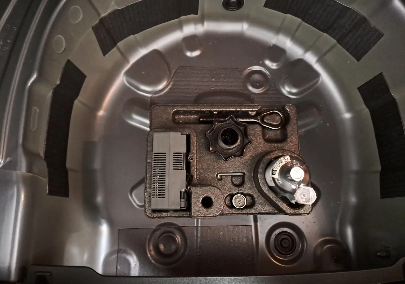 Coffre à outils de secours dans le compartiment de roue de secours d'une Volkswagen Polo gris cendre 2025.