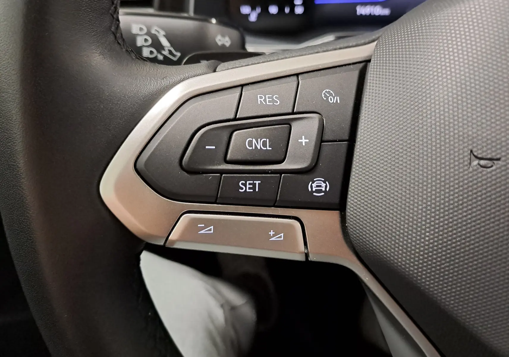 Gros plan sur les commandes de régulateur de vitesse au volant d'une Volkswagen Polo gris cendre 2025.