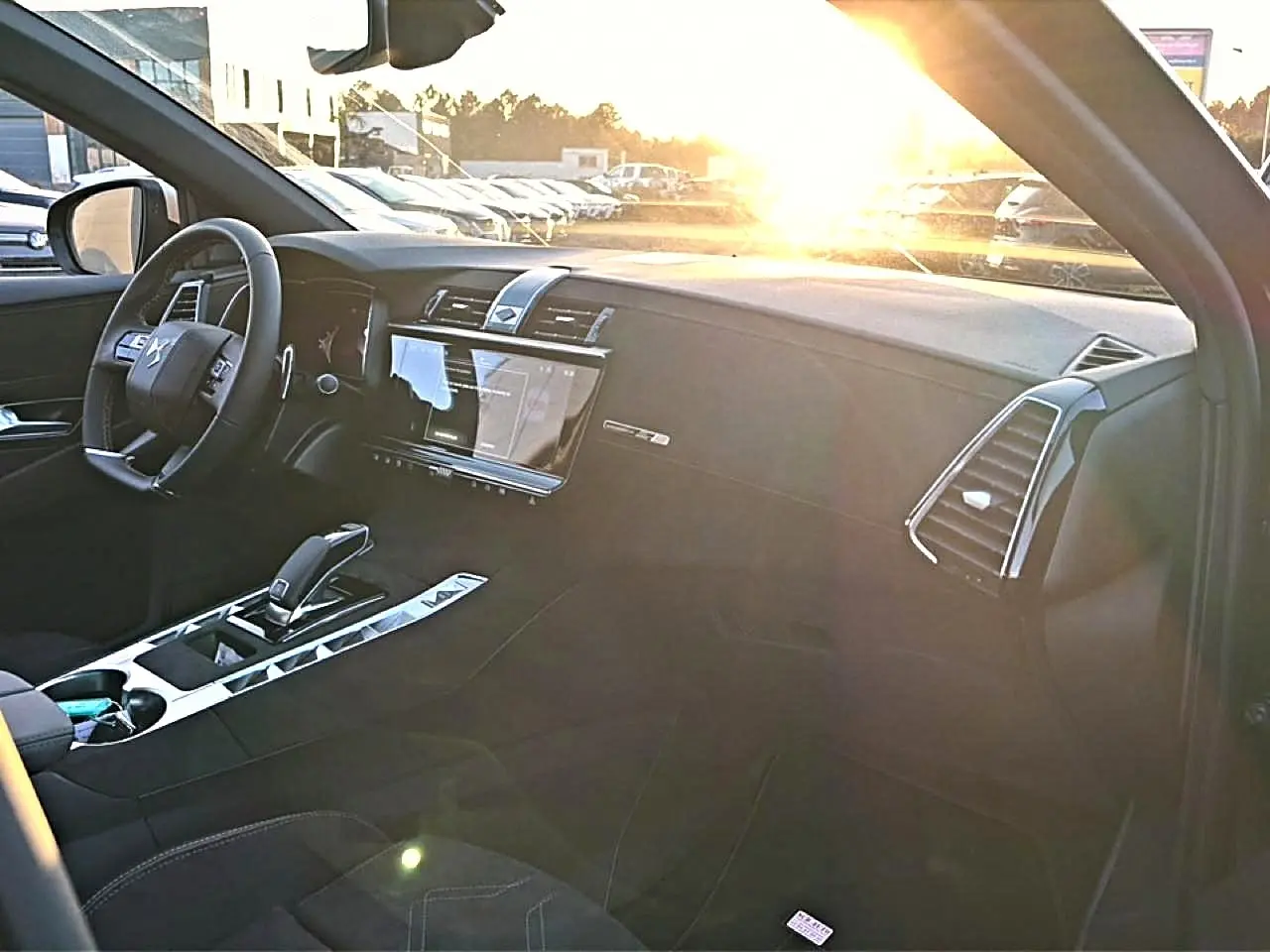 Intérieur noir du DS7 1.5 BlueHDi 130, vue côté passager avec tableau de bord et écran tactile au soleil couchant.