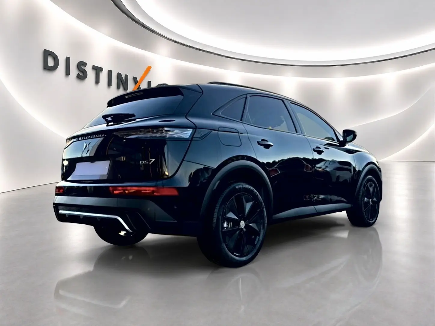 Vue 3/4 arrière droite du SUV DS7 noir brillant avec jantes noires dans un showroom lumineux.