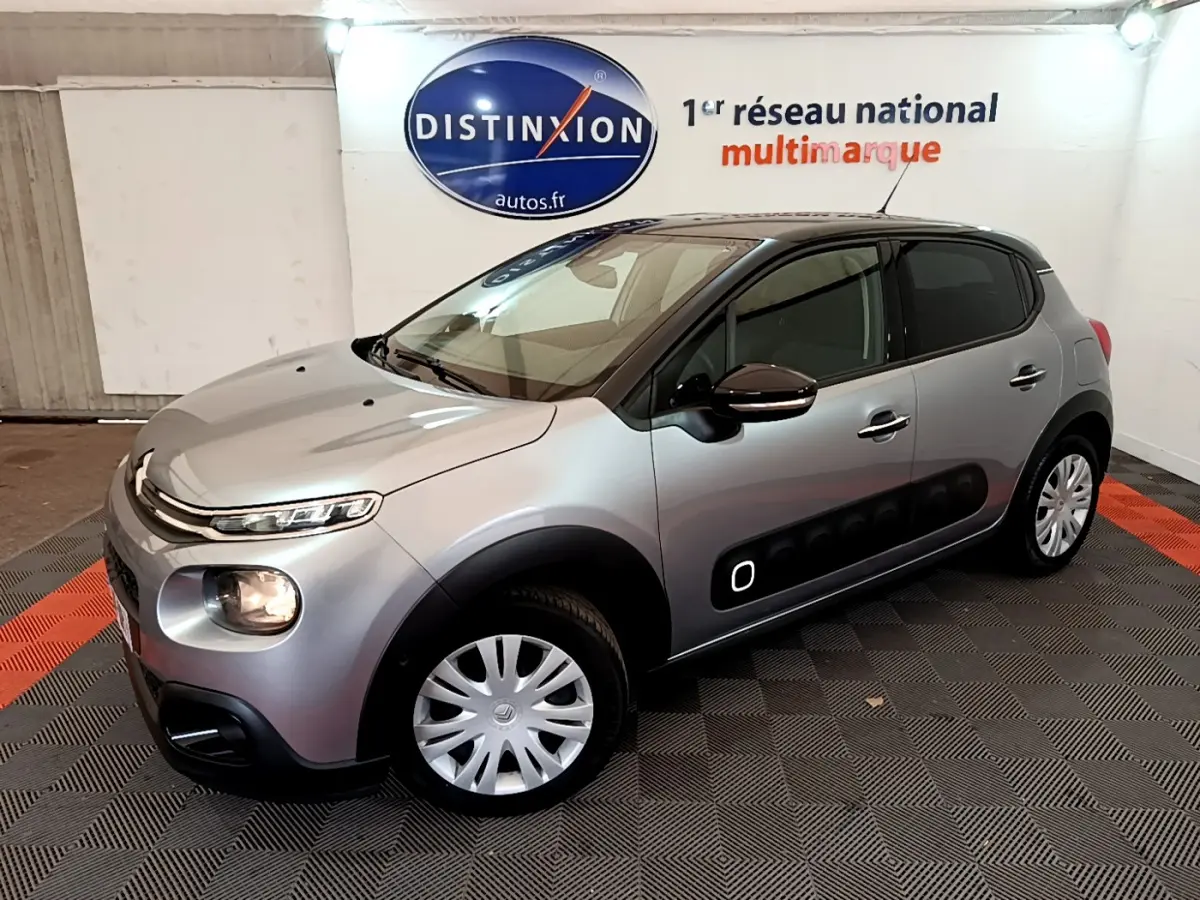 Citroën C3 gris clair vue 3/4 avant droit, avec protections latérales noires et jantes acier.