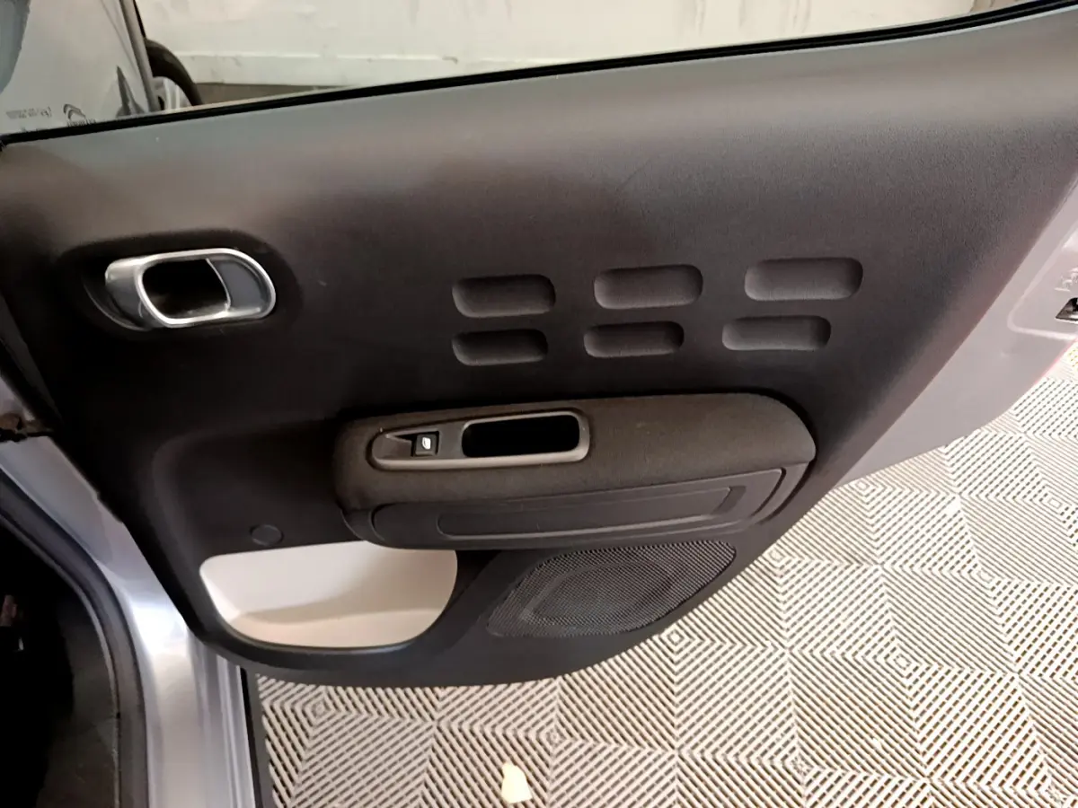 Vue rapprochée de la porte côté gauche gris clair de la Citroën C3 avec poignée argentée et panneau noir texturé.