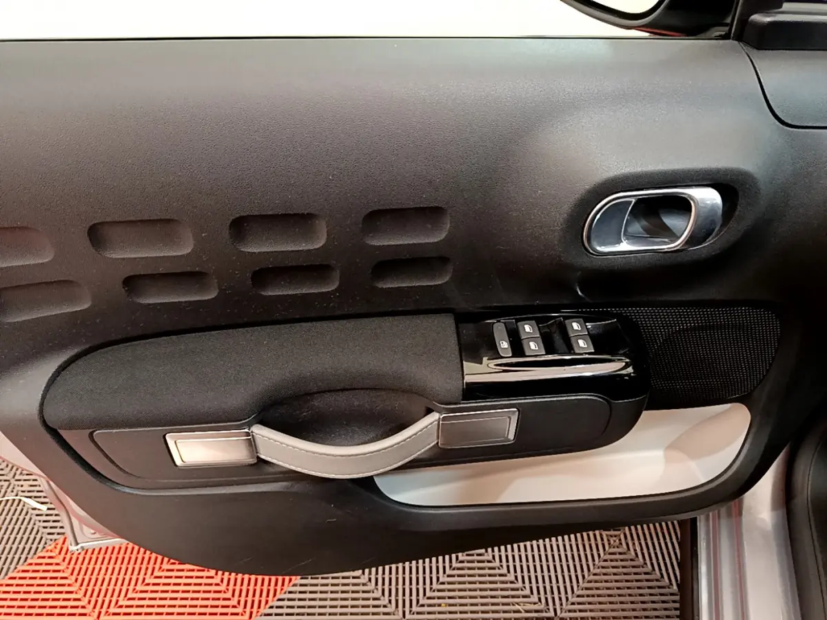 Vue rapprochée de la porte côté droit de la Citroën C3 gris clair, avec commandes de vitres et poignée intégrée.