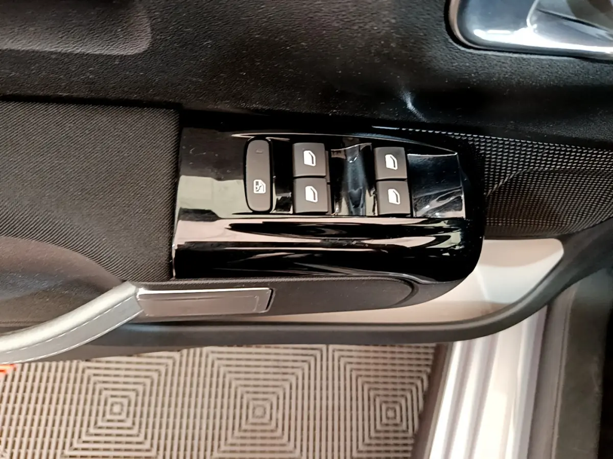 Commande des vitres électriques sur la porte côté conducteur d'une Citroën C3 gris clair, vue intérieure rapprochée.