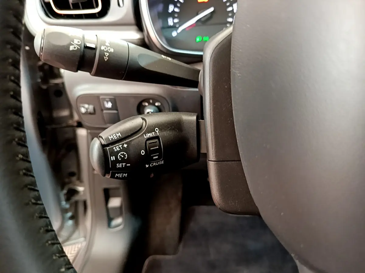 Gros plan sur les commandes de régulateur de vitesse et limiteur côté gauche du volant d'une Citroën C3 gris clair 2019.