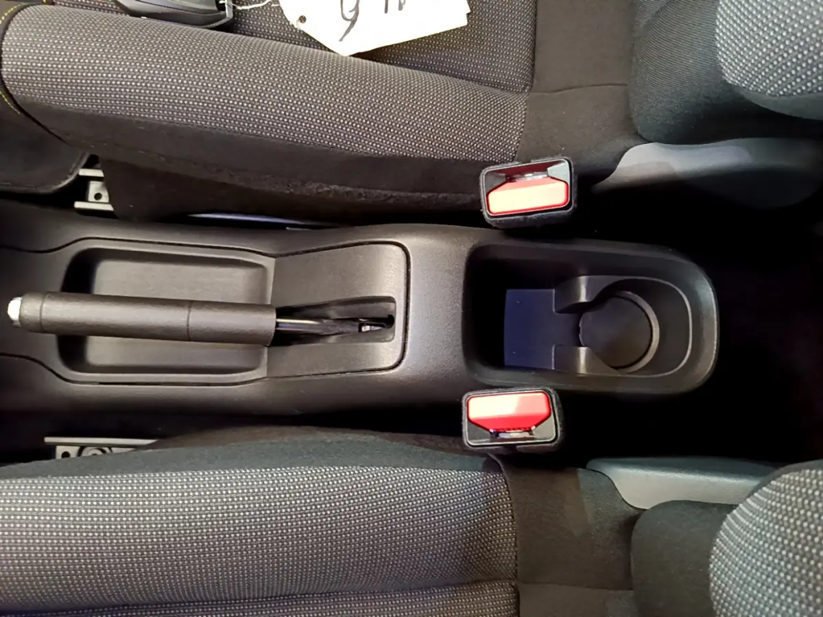 Vue plongeante sur la console centrale de la Citroën C3 2019, montrant frein à main et porte-gobelets entre sièges gris foncé.