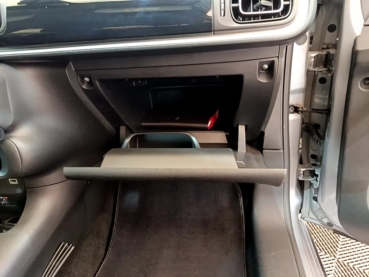 Gros plan sur la boîte à gants ouverte côté passager d'une Citroën C3 gris clair, intérieur noir.