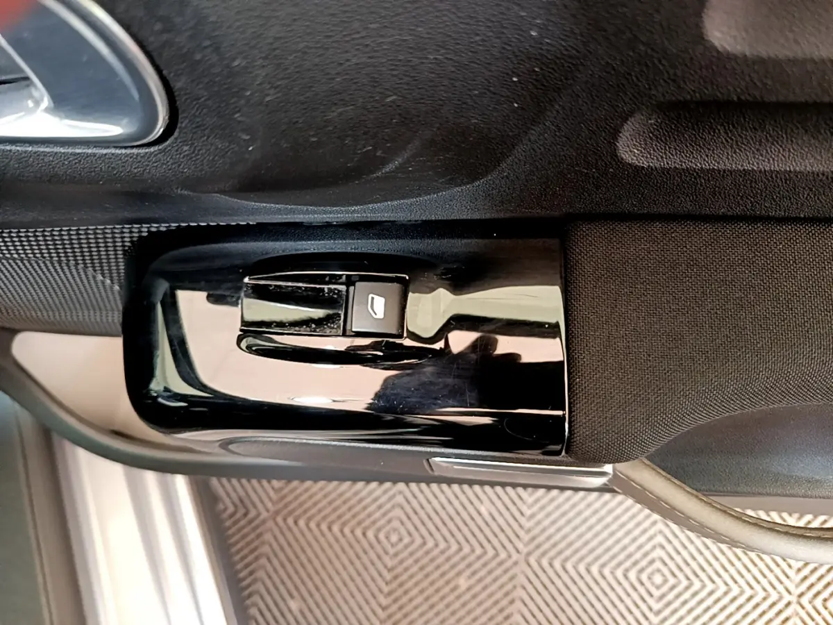 Gros plan sur la commande de lève-vitre côté conducteur d'une Citroën C3 2019, intérieur noir et gris.