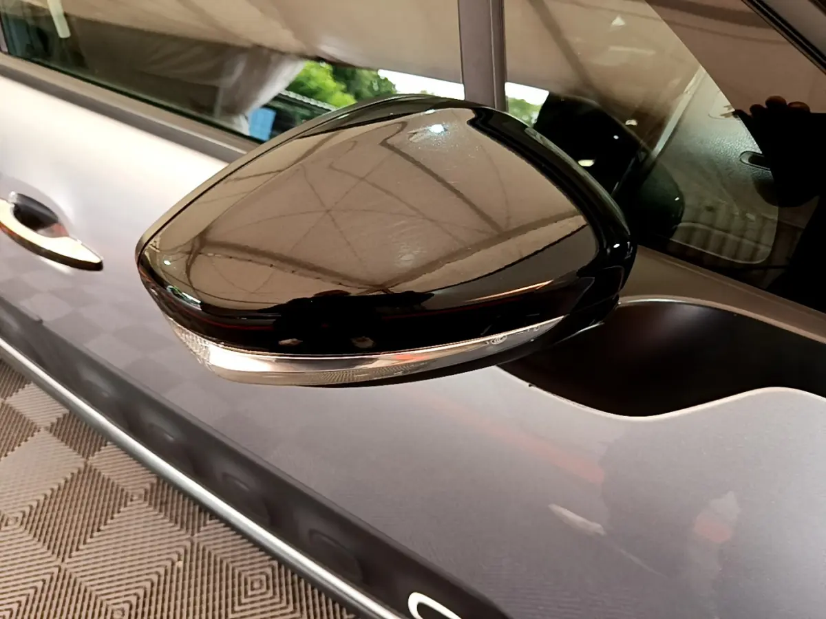 Rétroviseur noir brillant côté gauche d'une Citroën C3 gris clair, avec clignotant intégré visible.