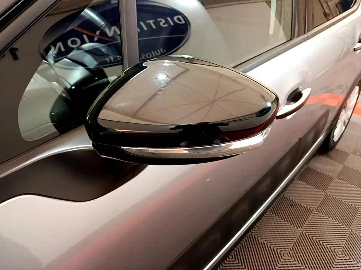 Rétroviseur noir brillant côté gauche d'une Citroën C3 gris clair, avec poignée de porte visible en arrière-plan.